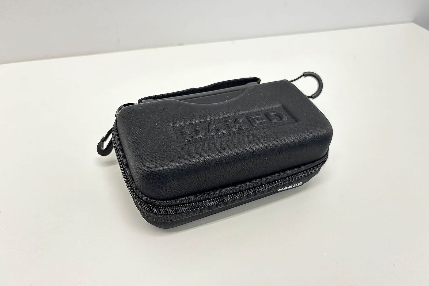 Naked Etui Ein schwarzes Brillenetui liegt auf einem weißen Tisch.